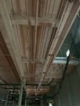 A wall of wooden slats with pipes running along the bottom.
