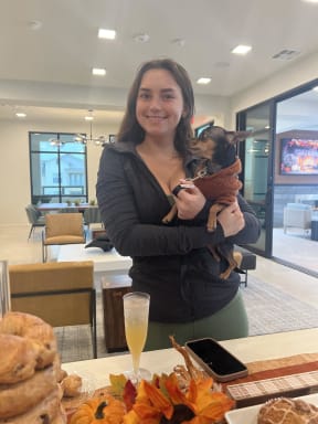 a woman holding a small dog in front of a table of food