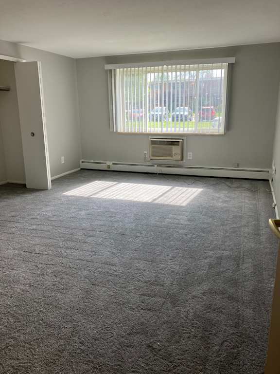 an empty living room with a large window and gray carpet