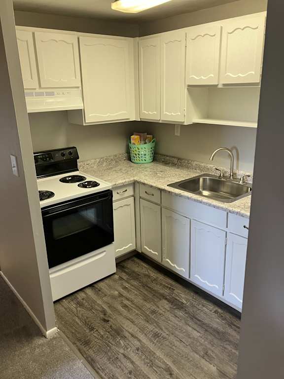 a small kitchen with white cabinets and a stove and sink