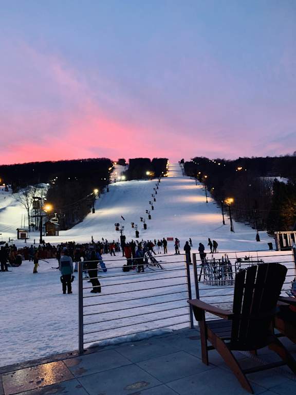 A chair is in the foreground of a snowy ski slope.