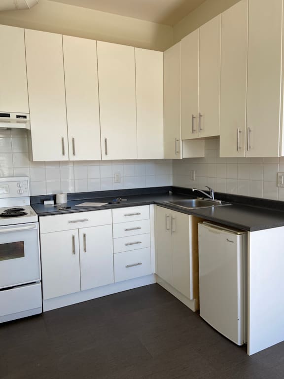 a kitchen with white cabinets and a black wall