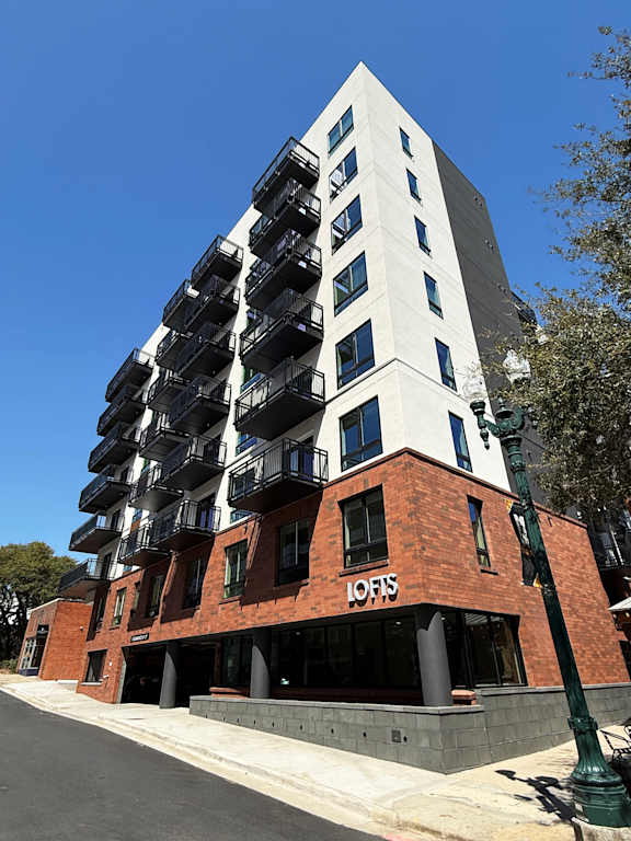 A tall building with a white top and a red base with the word "LOFIS" on it.