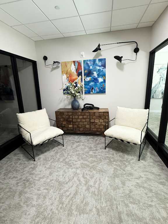 A room with two chairs and a table with a vase of flowers on it.