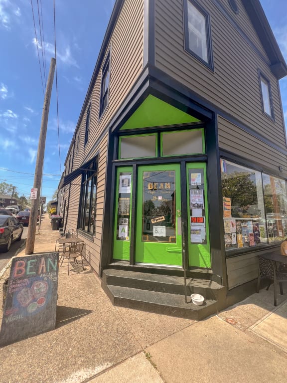 the front of a building with green doors and a sidewalk