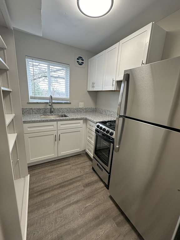 A kitchen with a stainless steel refrigerator, oven, and sink.
