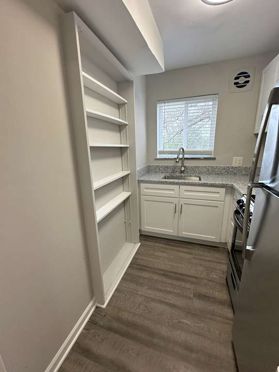 A kitchen with a sink, cabinets, and a refrigerator.