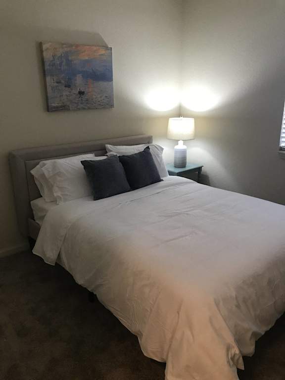a bedroom w at The Dakota Apartments, Florida 33458ith a bed and a lamp and a painting on the wall