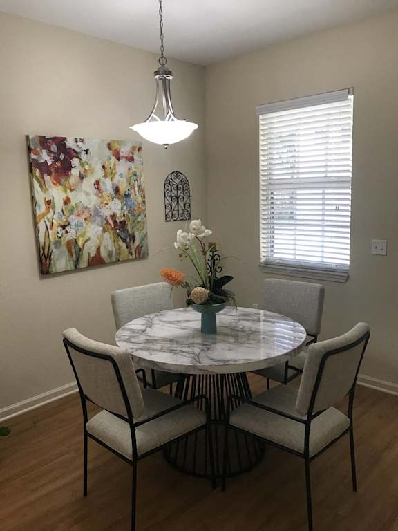 a dining ro at The Dakota Apartments, Florida 33458om with a table and chairs and a painting on the wall