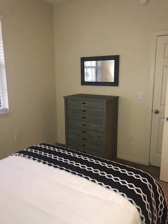 a bedroo at The Dakota Apartments, Florida 33458m with a bed and dresser with a mirror on the wall