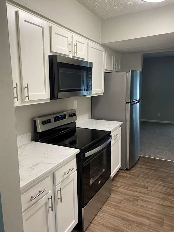 A kitchen with white cabinets and black appliances.