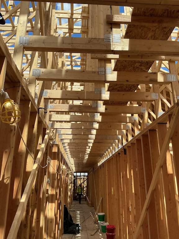 A long hallway of a building under construction with wooden beams and no walls.
