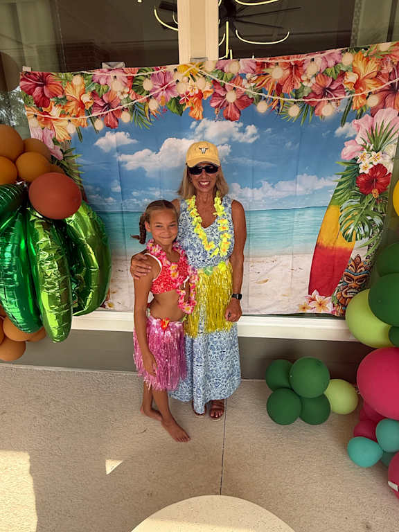 Two people in Hawaiian shirts and grass skirts are posing for a photo.