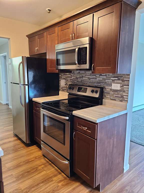 Rehabbed kitchen with cherry  cabinets and glass backsplash