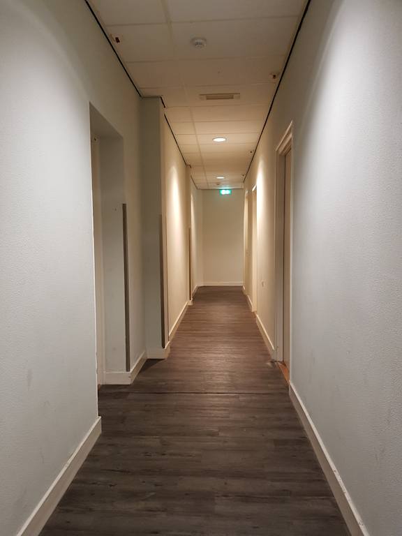 A long hallway with a green light at the end.