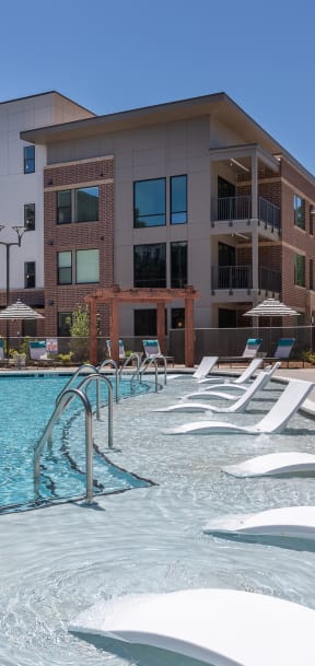 a swimming pool with white chairs in front of an apartment building  at Link Apartments® Canvas, Atlanta
