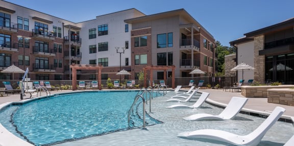 a swimming pool with white chairs in front of an apartment building  at Link Apartments® Canvas, Atlanta