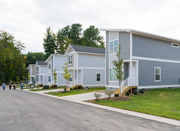 A row of houses with people walking in front.