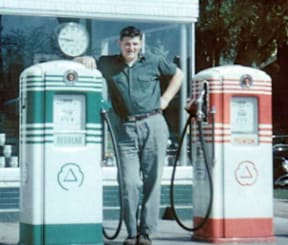 A man standing between two gas pumps.