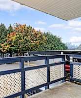 A view from a balcony overlooking a parking lot and trees.