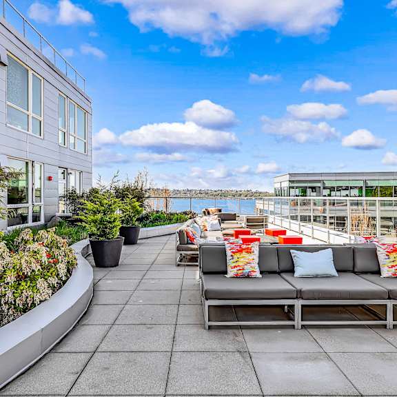 A modern outdoor seating area with a metal bench and potted plants.