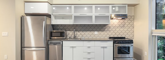 a kitchen with white cabinets and stainless steel appliances and a window