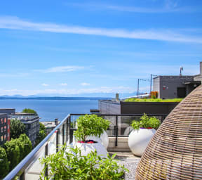 a terrace with two wicker chairs and a rug with a view of the water