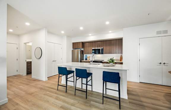 A kitchen with a white island and blue chairs.