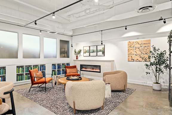 A living room with a fireplace, chairs, and a rug.
