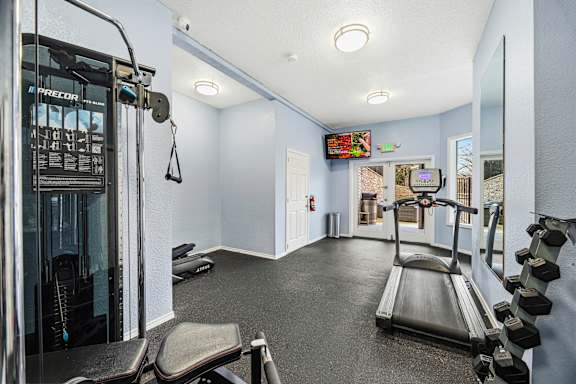 A gym with orange walls and a variety of exercise equipment.