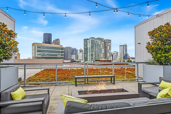 the rooftop patio with couches and a fire pit and a view of the city