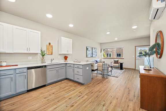 A kitchen with wooden floors and white cabinets.