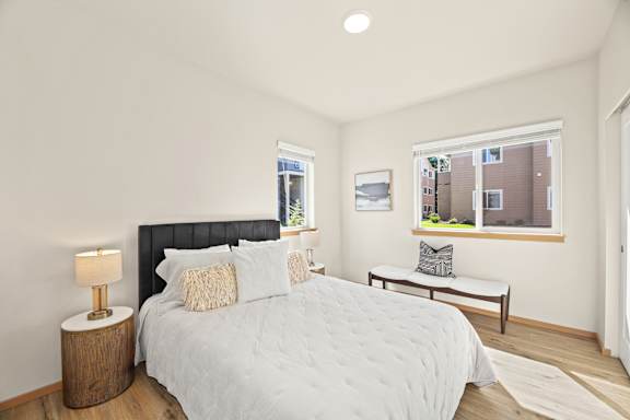 A bedroom with a large bed and a window overlooking a building.