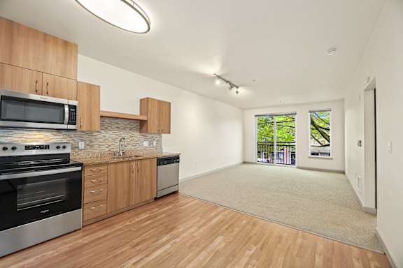a kitchen with wooden cabinets and appliances and a door to a living room