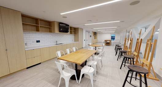 A room with a long table and chairs and a TV mounted on the wall.
