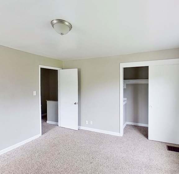 A room with a carpeted floor and a window on the right side.