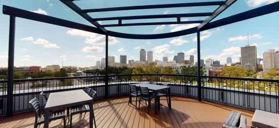 a balcony with a view of a city and a table and chairs