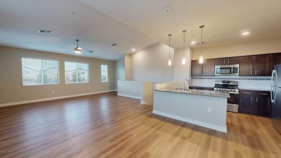 an empty living room and kitchen with wood floors
