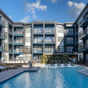 A large swimming pool in front of a modern apartment building.