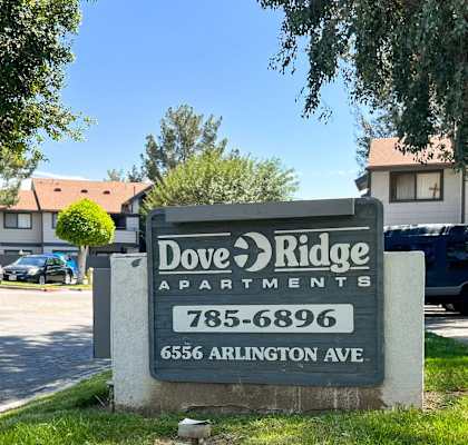 a sign for doe ridge apartments sits in front of a parking lot