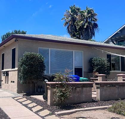 a house with a gray roof and a sidewalk in front of it