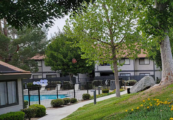 a building with a pool in the background and trees in the foreground