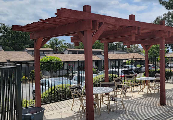 a wooden pergola with tables and chairs under it