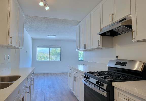 A kitchen with white cabinets and a black stove top oven.