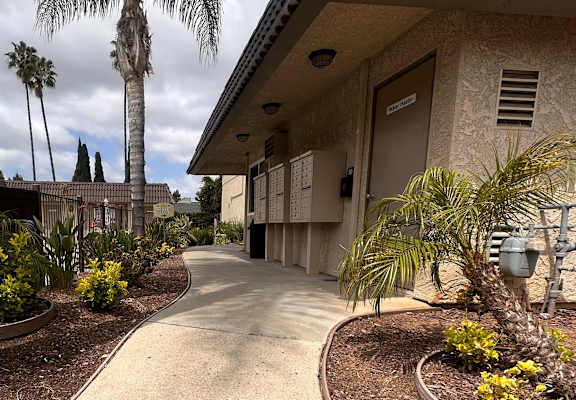 a walkway in front of a building with palm trees in the background