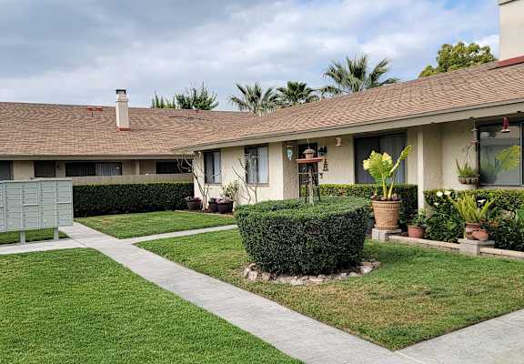 a house with a grassy yard and a hedge in front of it