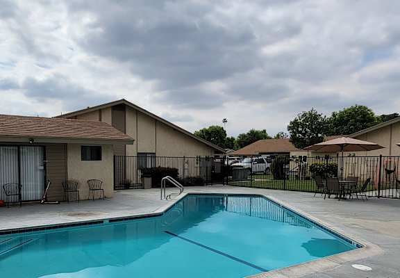 a swimming pool with chairs and umbrellas in front of a building