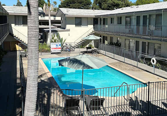 a swimming pool with an umbrella in front of a building