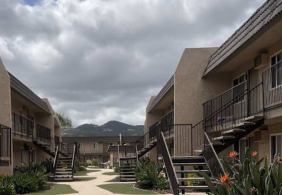 a pathway between two apartment buildings with a mountain view in the background