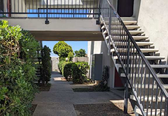 a view of the outside of a building with a staircase and bushes
